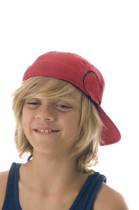 Caucasian boy of ten with long blond hair has toothy grin, wearing red baseball cap backwards