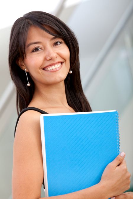Beautiful female student smiling and holding a notebook