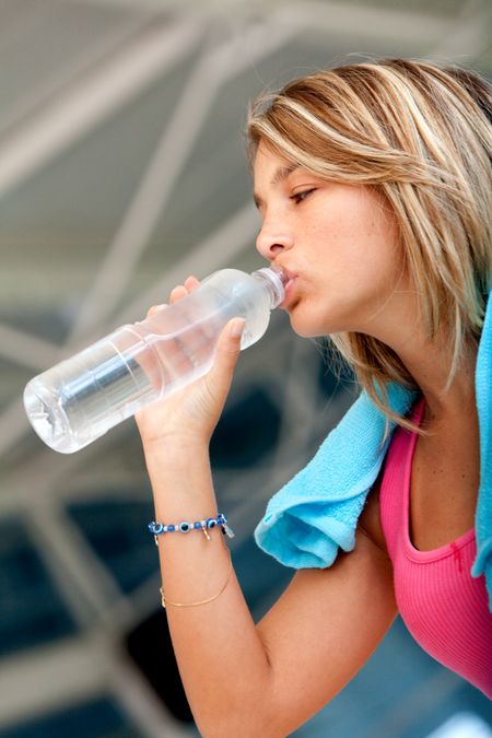 Gym woman drinking water after working out