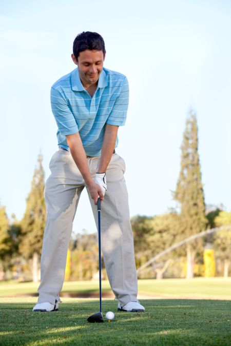 Young man playing golf leaning on the club and smiling