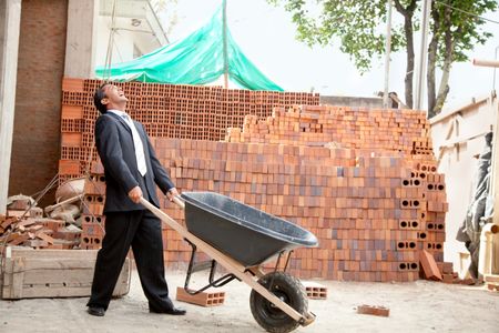 Elegant engineer with a wheelbarrow in a construction site
