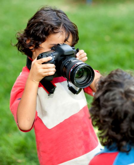 Boy taking pictures and playing with a camera outdoors
