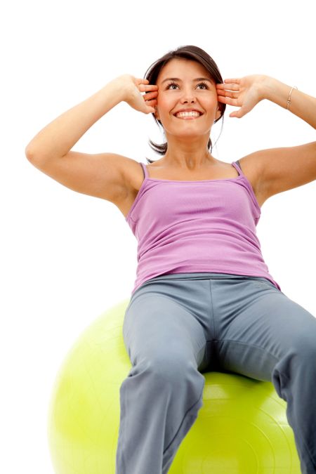 Fit woman exercising with a pilates ball - isolated over a white background