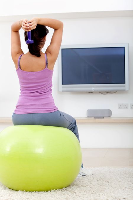 Woman exercising at home in front of the tv