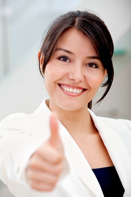 Beautiful business woman smiling in her office with thumb up