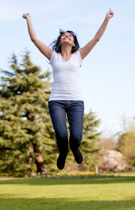 Happy woman outdoors - Jumping full of joy with her arms up