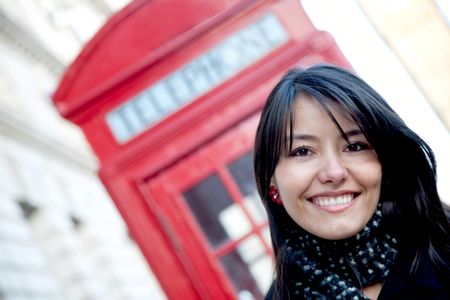 Woman smiling outside a telephone booth in London