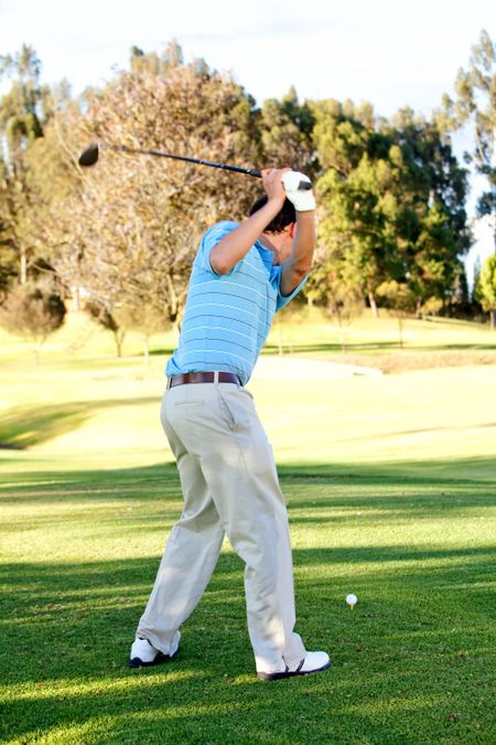 Male golf player at the course hitting the bal
