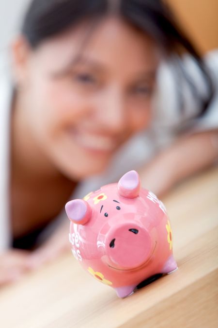 Business woman looking at a piggybank and smiling