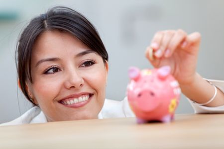 Business woman putting a coin into a piggybank and smiling