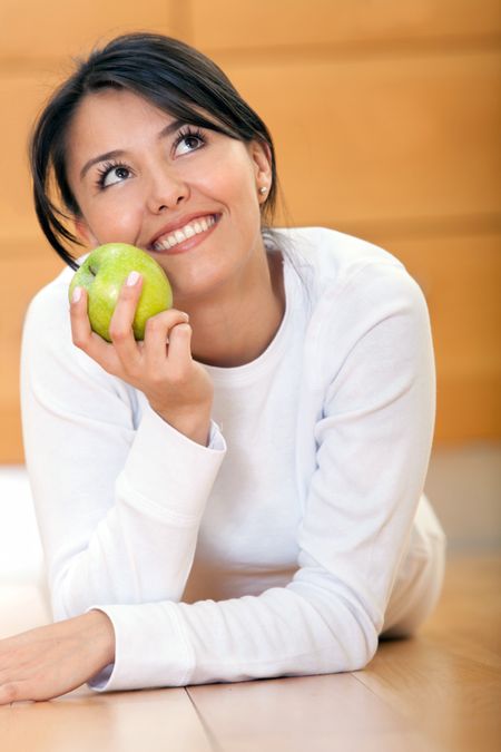 Beautiful pensive woman holding an apple and smiling