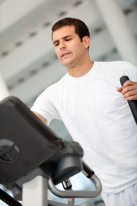 Beautiful gym man exercising on a cardio machine smiling