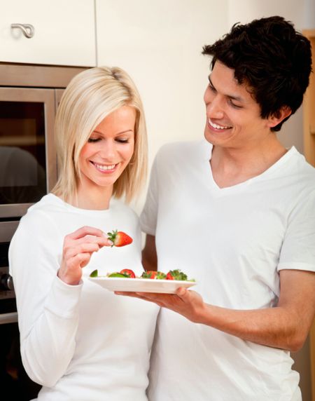 couple in the kitchen eating strawberries- healhy lifestyle concepts
