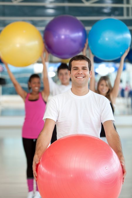 Group of people at the gym smiling with a pilates ball
