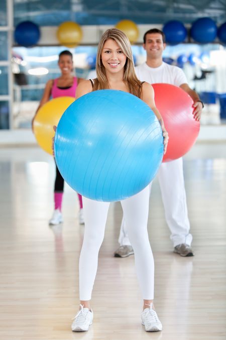 Group of people at the gym smiling with a pilates ball