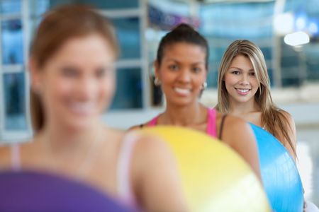 Group of women at the gym smiling with a pilates ball