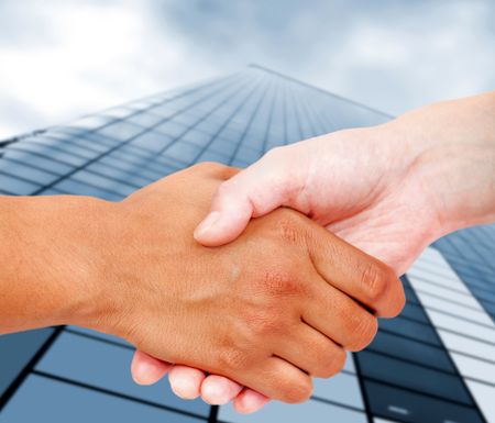 Close up of a business handshake with an office building behind