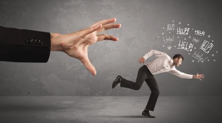 Business person running away from big hand while asking for help concept on background