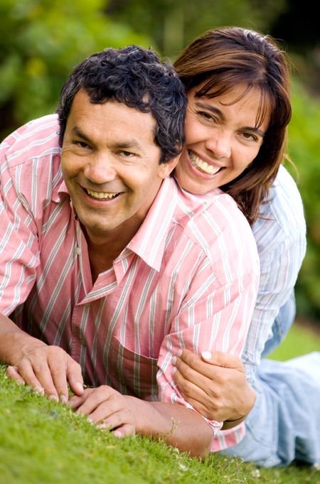couple portrait on the floor outdoors where both are smiling and looking happy