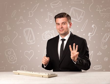 Young handsome businessman sitting at a desk with white mixed media icons behind him