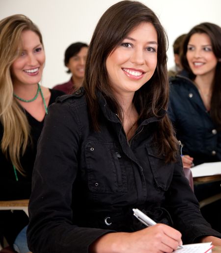Female student in the classroom with a notebook and smiling