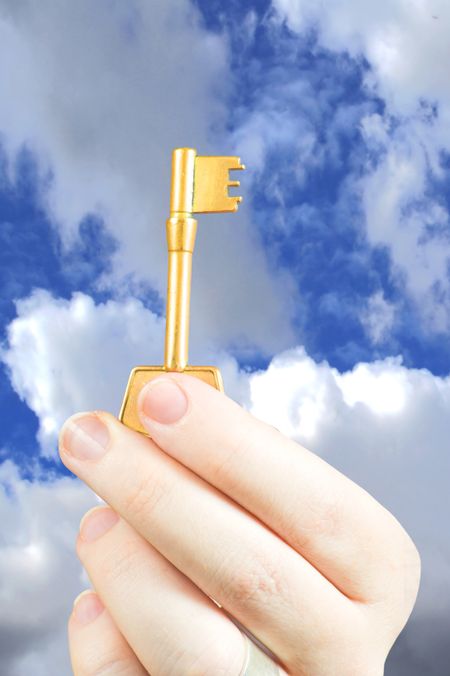 Hand holding a key of success over a cloud background