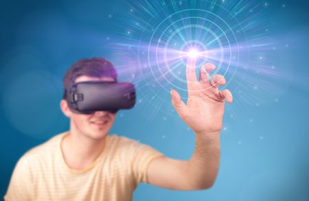 Young impressed man wearing virtual reality goggles with blue circles around his finger 