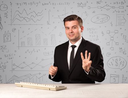 Young handsome businessman sitting at a desk with white charts behind him