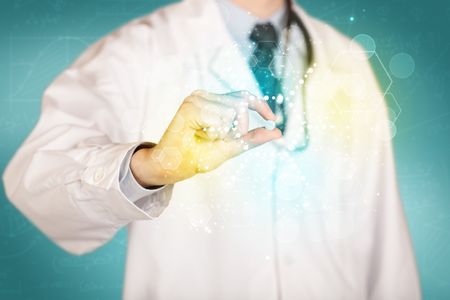 A male doctor in white coat with a stethoscope holding a pill with glowing colorful dots and lines