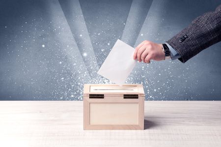 Ballot box with person casting vote on sparkling background