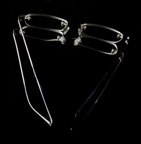Pair of reading glasses on dark reflective background