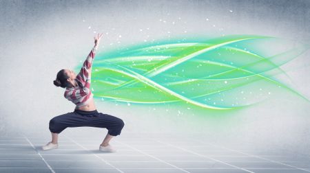 A good looking fresh street dancer dancing in front of grey background with white and bright, colorful green lines concept