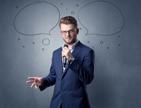 Businessman speaking into microphone with speech bubbles over his head