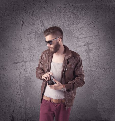A Hipster Fashion Model Guy In Casual Clothing Stnading With Mobile Phone In Front Of Concrete