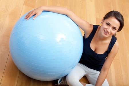 Fit woman at the gym smiling with a pilates ball