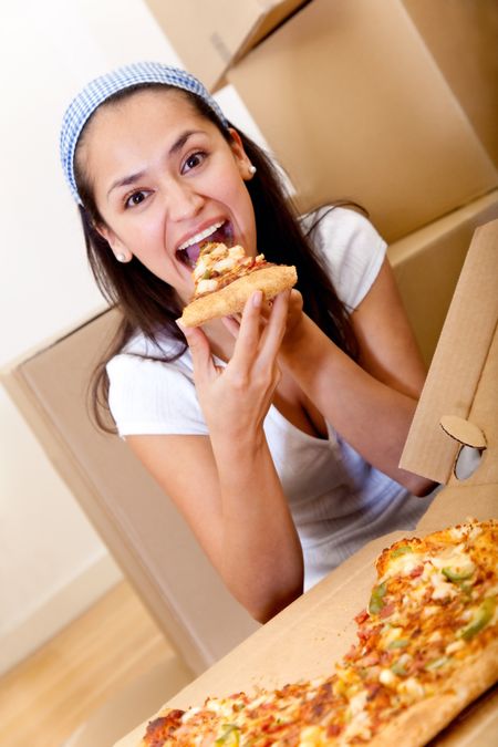Young woman eating pizza while taking a break from packing