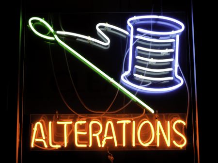 Neon sign depicting needle and spool of thread in window of dry cleaners