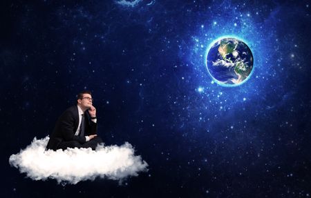 Caucasian businessman sitting on a white fluffy cloud looking and wondering at planet earth