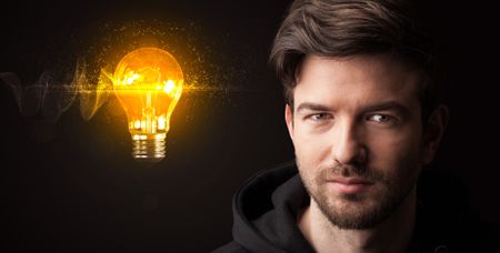 Portrait of a young businessman with a lightbulb next to him on a dark background