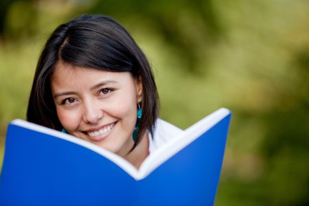 Woman studying outdoors with a notebook and smiling