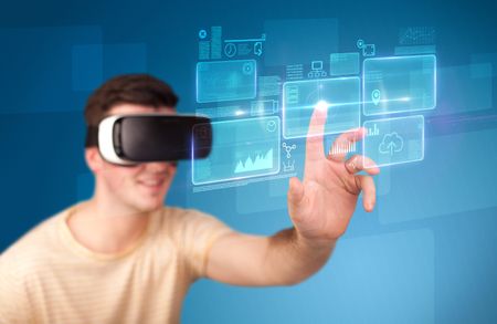 Young impressed man wearing virtual reality goggles with blue squares containing data at his fingers 
