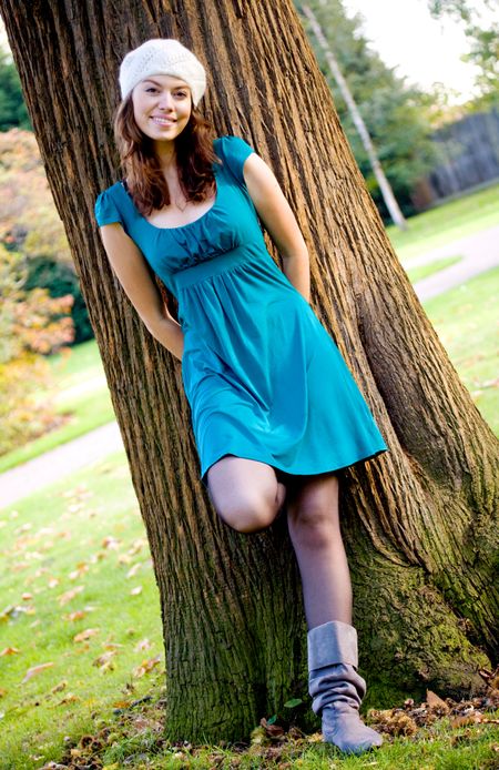 beautiful fashion woman in a park leaning against a tree