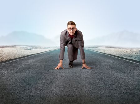 Young determined businessman kneeling before blank running track 
