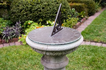 Sundial on pedestal by garden paths