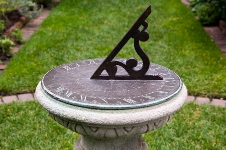 Sundial on pedestal by garden path