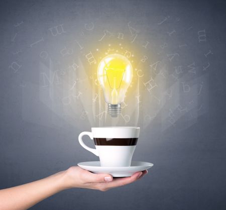 Young female hand holding coffee cup with a lightbulb and alphabet letters above it 