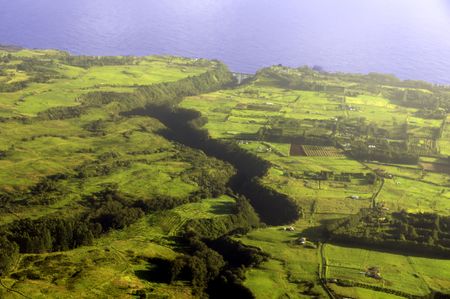Aerial view of long deep valley cutting across farmland early in the morning, Big Island of Hawaii