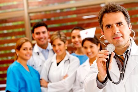 Doctor holding a stethoscope at the hospital with a  group behind