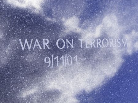 Inscription on anonymous public monument, with start date of September 11, 2001, indicates the war on terrorism continues to go on (reflection of sky on polished face of granite slab)