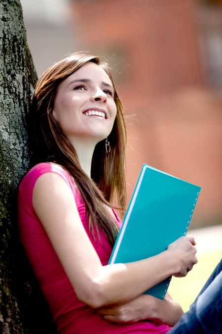 Pensive female student with a notebook outdoors